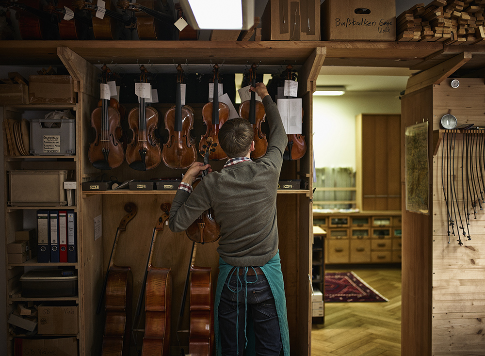 Violin maker in his workshop with restored violins